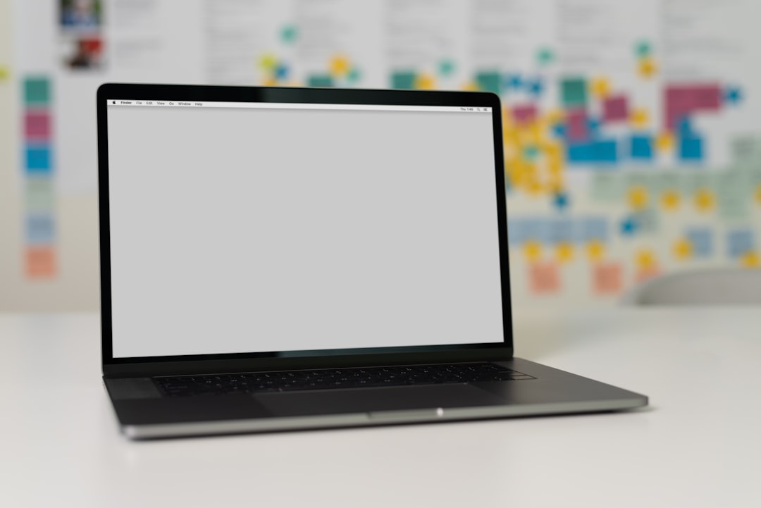 A laptop on a table with a blurred background of colorful sticky notes on a wall